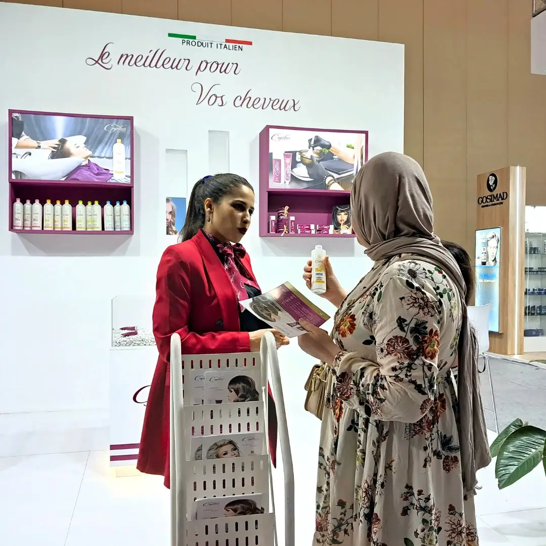 An exhibitor shows a range of hair care products to a visitor