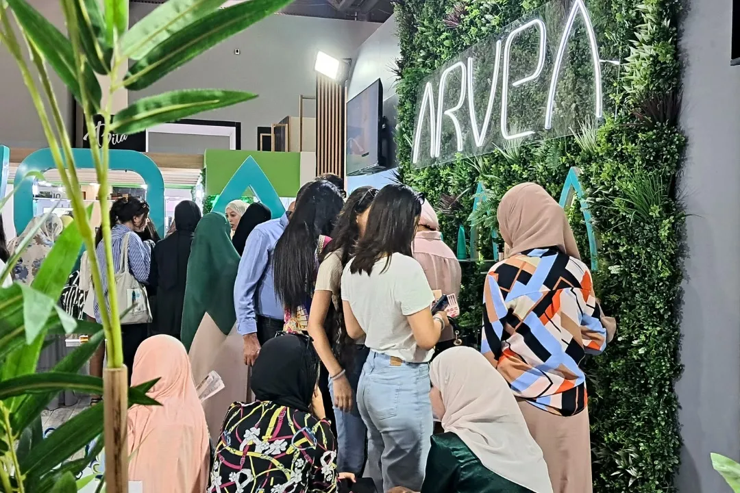 A crowd in front of a stand’s green wall at CosmeOran 2024