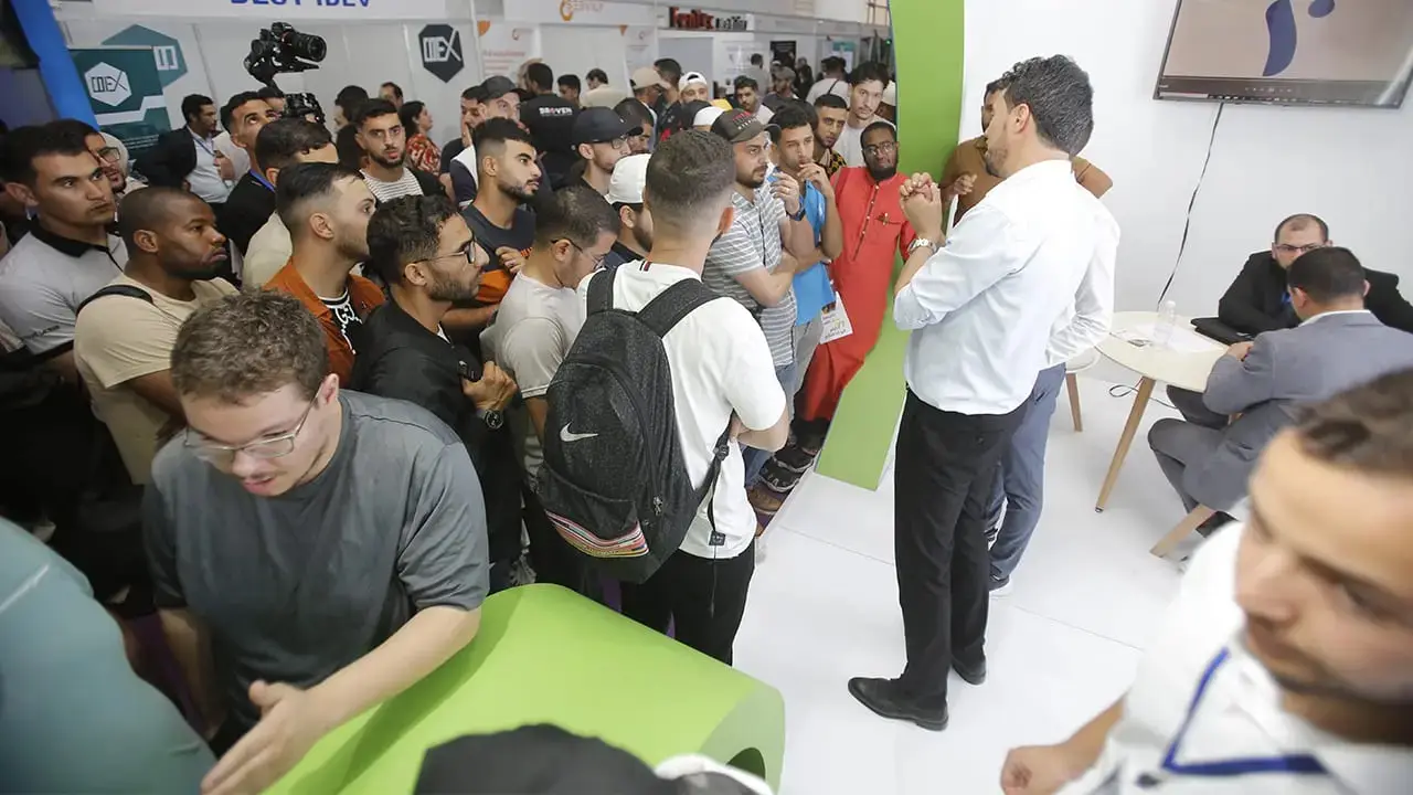 Visitors gathered around a stand at ECSEL Expo Algiers 2024, in front of a camera