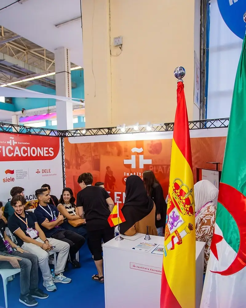 Visitors at the Instituto Cervantes stand, with the Spanish and Algerian flags in front
