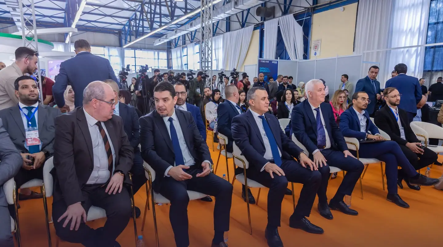 Officials in the front row of a session, television cameras at the back